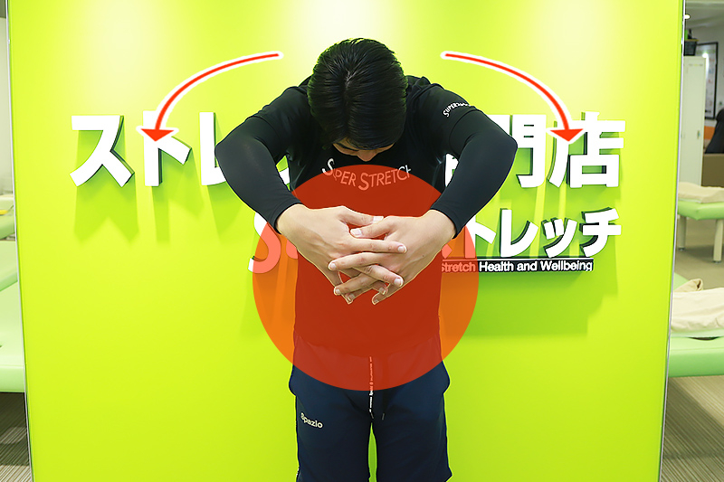大きなボールを抱え込むイメージで両手を体の前で組み、肩甲骨まわりの筋肉を伸ばします。